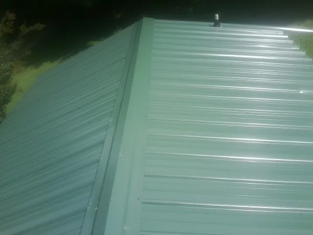New green metal panels meeting at the ridge of a roof — Flat Roof Repair work by our crew in Wilsonville