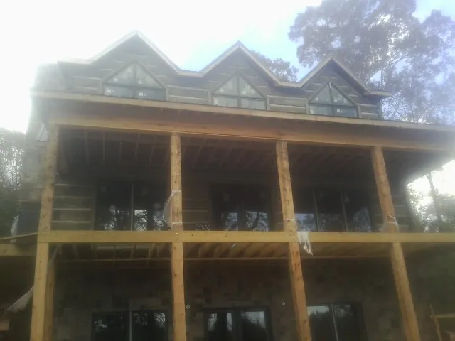 Dormers and porch framing on a large log home under construction — Roof Coating work by our crew in Wilsonville