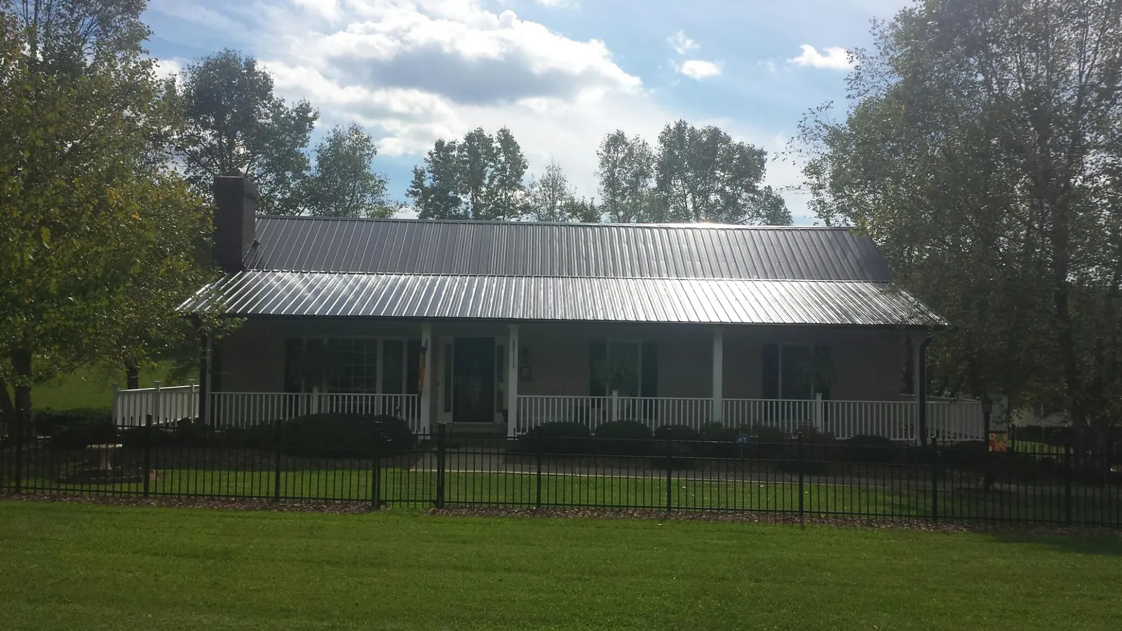 Gray metal roof on a brick ranch with a full width front porch — Gutter Guard Installation work by our crew in Wilsonville